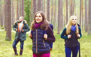 Young happy friends walking in forest and enjoying a good autumn day. Camp, tourism, hiking, trip, concept.