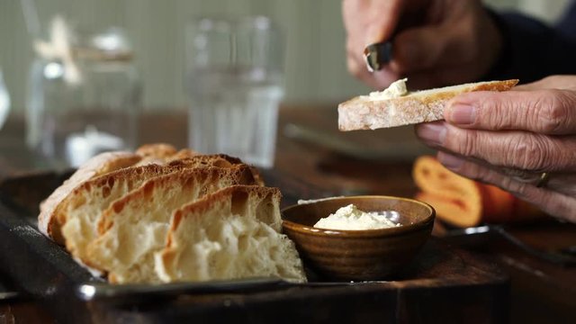 Hand spreading butter on fresh bake bread rustic food style