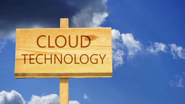 Cloud technology words on a wooden sign against time lapse clouds in the blue sky