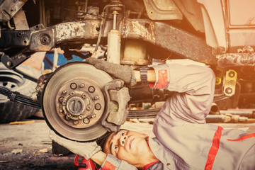 Technicians in grey uniform are repairing the brake of the car, Automotive industry and garage concepts.