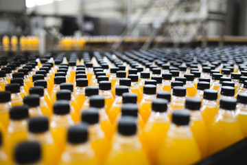 Industrial factory indoors and machinery. Robotic factory line for processing and bottling of soda and orange juice bottles. Selective focus. Short depth of field.