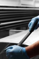 Man filing deburring a metal panel with a file