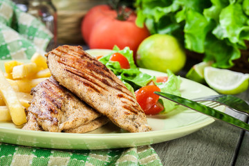 Grilled chicken breasts served with fries