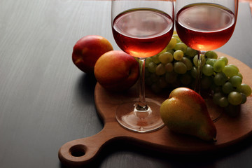 Glasses with pink wine and fruit..