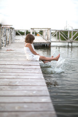 girl child on wooden bridge on lake, childhood,