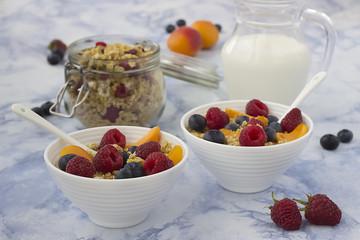 Bowls of  granola  with  fresh fruit on marble table.