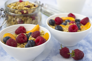 Bowls of  granola  with  fresh fruit on marble table.