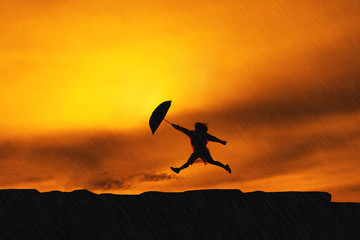 Young girl asian jumping with raincoat and umbrella on mountain in the rainy season silhouette
