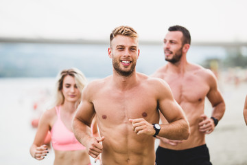 Group of young attractive people fitness workout. They having fun and running at beach.