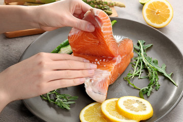 Woman marinating salmon fillet on plate