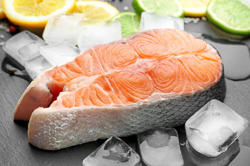 Fresh salmon steak with ice cubes on slate plate