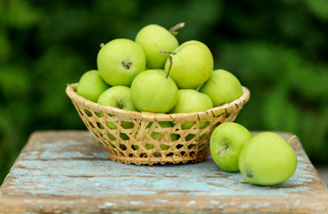 Homemade rustic green apples in a basket on an old stool.