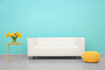 White sofa, table and ottoman near color wall