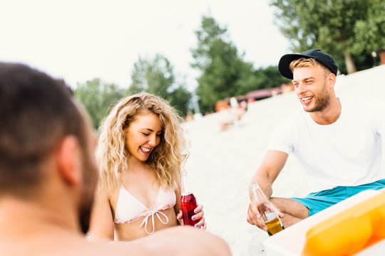 Group of attractive young people enjoying at beach, drinking and toasting.