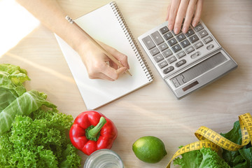Young woman calculating calories at table. Weight loss concept