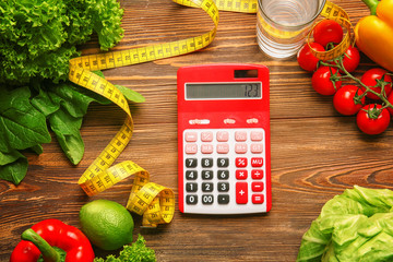 Calculator, measuring tape and set of healthy food on wooden table