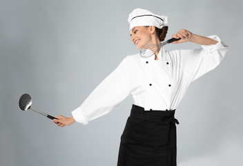 Naklejka premium Young female chef with utensils on light background