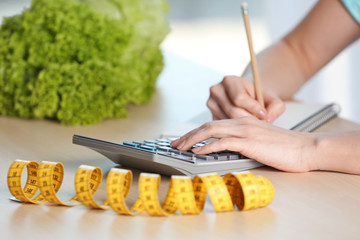 Young woman calculating calories at table. Weight loss concept