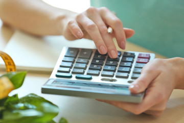 Young woman calculating calories at table. Weight loss concept