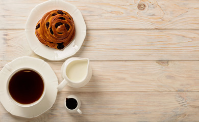 Cups with tea and biscuits on a light wooden background.