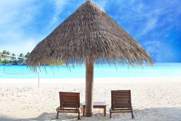 Sun loungers and umbrella on sea beach at resort
