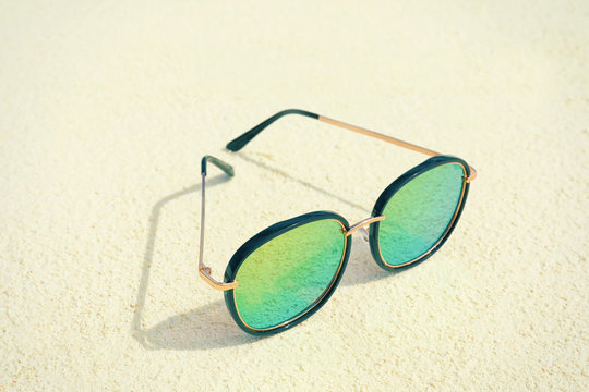 Modern sunglasses on beach sand. Summer vacation concept
