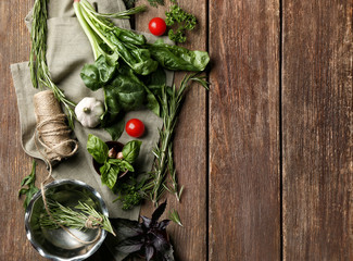 Composition with fresh herbs and vegetables on wooden background