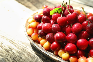 Plate with fresh ripe cherries on wooden table