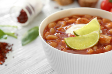 Bowl with delicious turkey chili on wooden table, closeup