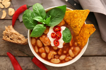 Composition with delicious turkey chili in bowl on wooden table
