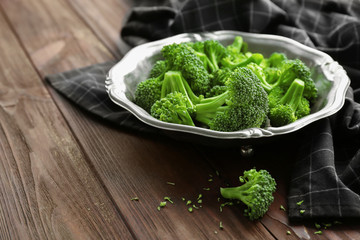Metal plate with fresh green broccoli and napkin on table