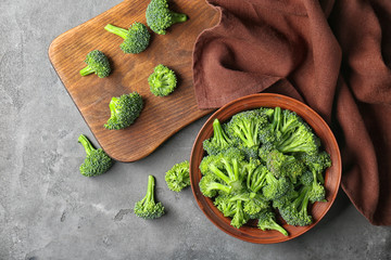 Bowl with fresh green broccoli and wooden board on table