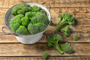 Colander with fresh green broccoli on table