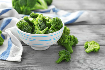 Bowl with fresh green broccoli and napkin on table