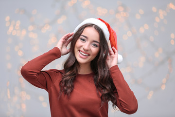 Pretty emotional lady in Christmas hat on blurred background