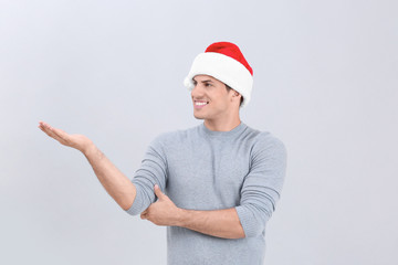 Handsome man in Christmas hat on light background
