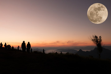 Fototapeta premium silhouette of people the cliff and looking at the valley and mountain with full moon