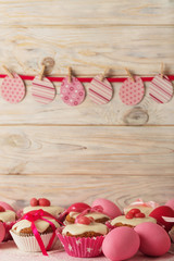 Easter cupcakes with white icing decorated with pink candy and ribbons.