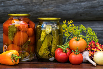 Fototapeta na wymiar Canned tomatoes and cucumbers with fresh vegetables