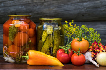 Fototapeta na wymiar Canned tomatoes and cucumbers with fresh vegetables
