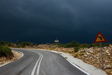 Mountain road at Kastro, Thassos island - driving into the storm - road with sharp turn ahead and dark storm clouds in the far distance - powerful image