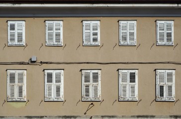 Traditional european  wooden shutters on a   brown facade of an old  residential building
