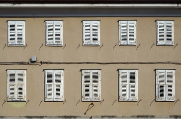 Traditional european  wooden shutters on a   brown facade of an old  residential building
