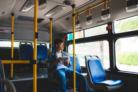 Young man sitting in city bus and reading a book.