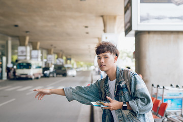 Attractive asian man calling a taxi at the airport