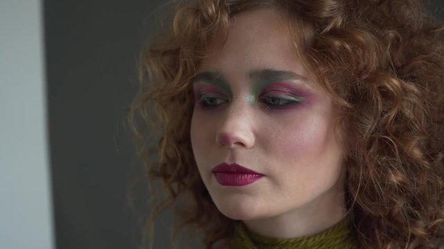 Close-up view to the professional makeup artist is applying red lip gloss to a model.