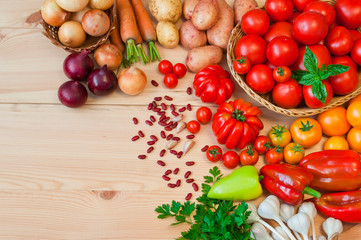 Tomatoes, carrots, potatoes and other fresh vegetables on a wooden table