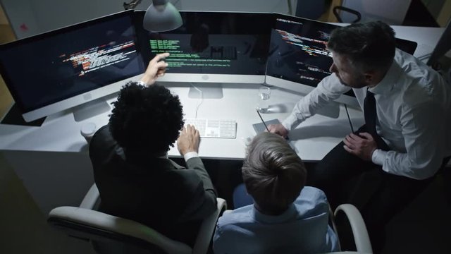 Top view of IT security team working with programming code on multiply monitor computer in the office at night