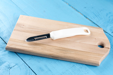 Brand new peeling knife on the kitchen cutting wooden board