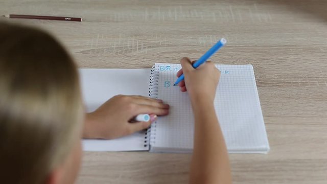 Girl write back to school in notebook with misspelling. Young girl sitting by desk table. White girl write letters with mistake. Fix mistake by felt-pen. Home work schoolgirl write down.